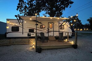 Ein Wohnmobil mit überdachter Terrasse, Sitzgelegenheiten und Lichterketten.