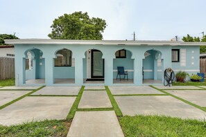 A light blue house with a patio, a door, and a chair. - FIU Basecamp: Miami Home w/ Fenced Yard! (Miami)