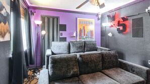 A room with a grey sofa, a ceiling fan, and a poster of Houston, Texas. - Games & Yard! Family Home Near Kemah Boardwalk (Dickinson)