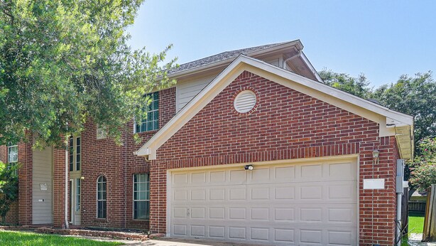 A two-story brick house with a front garage, a small porch, and a well-maintained lawn. - Games & Yard! Family Home Near Kemah Boardwalk (Dickinson)