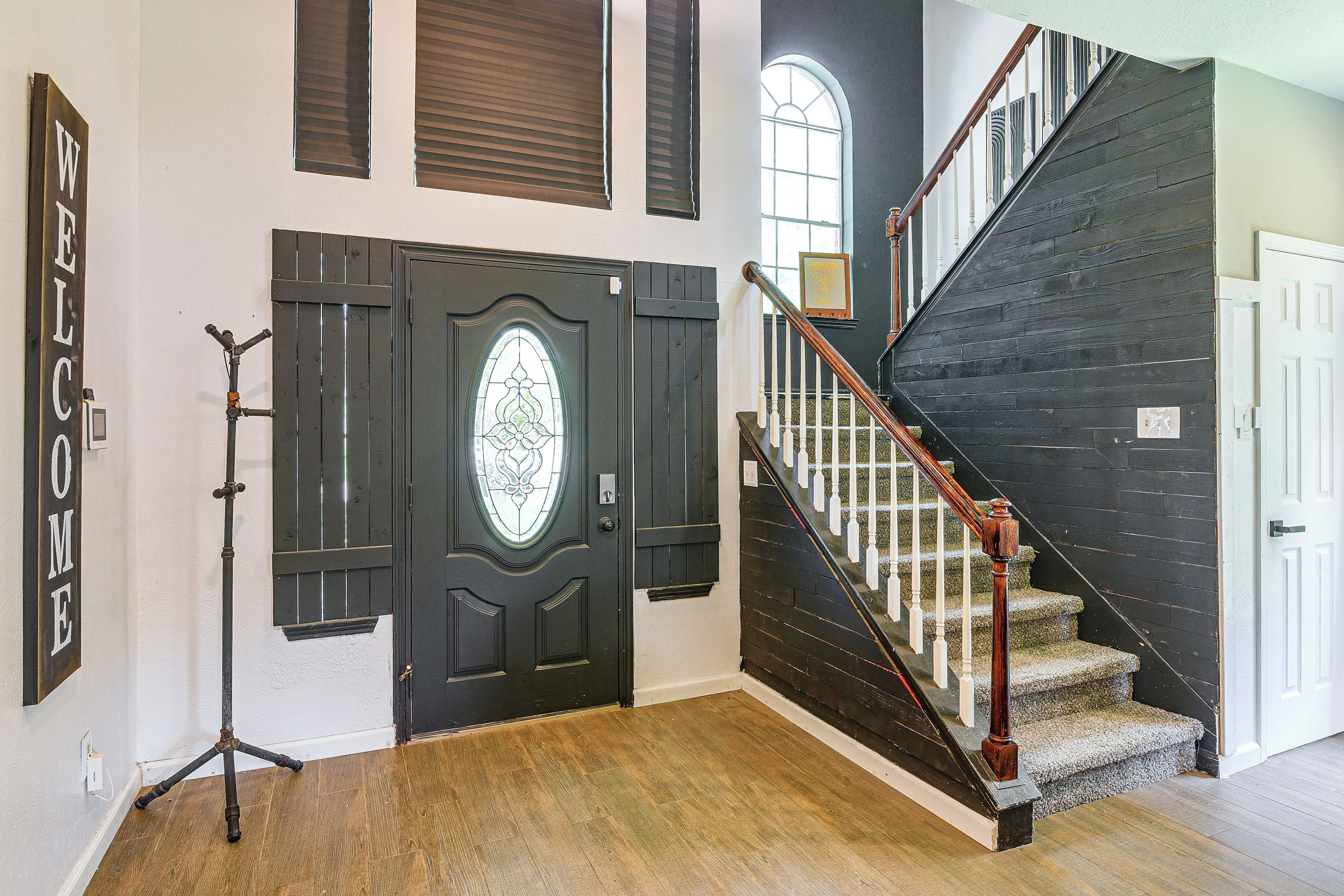 A staircase with a dark wooden finish and white balusters, leading to a white door with a decorative glass panel.