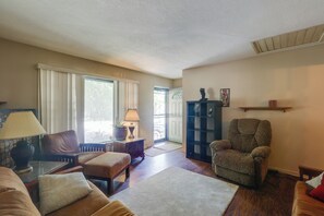 A living room with a sofa, armchair, and a small table with a lamp. There is a door leading to a balcony. - 4 Mi to Dtwn Wichita! 'Else House' w/ Yard & Patio (Wichita)