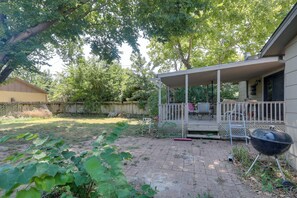 Un jardin avec un patio couvert, un barbecue et une clôture en bois.