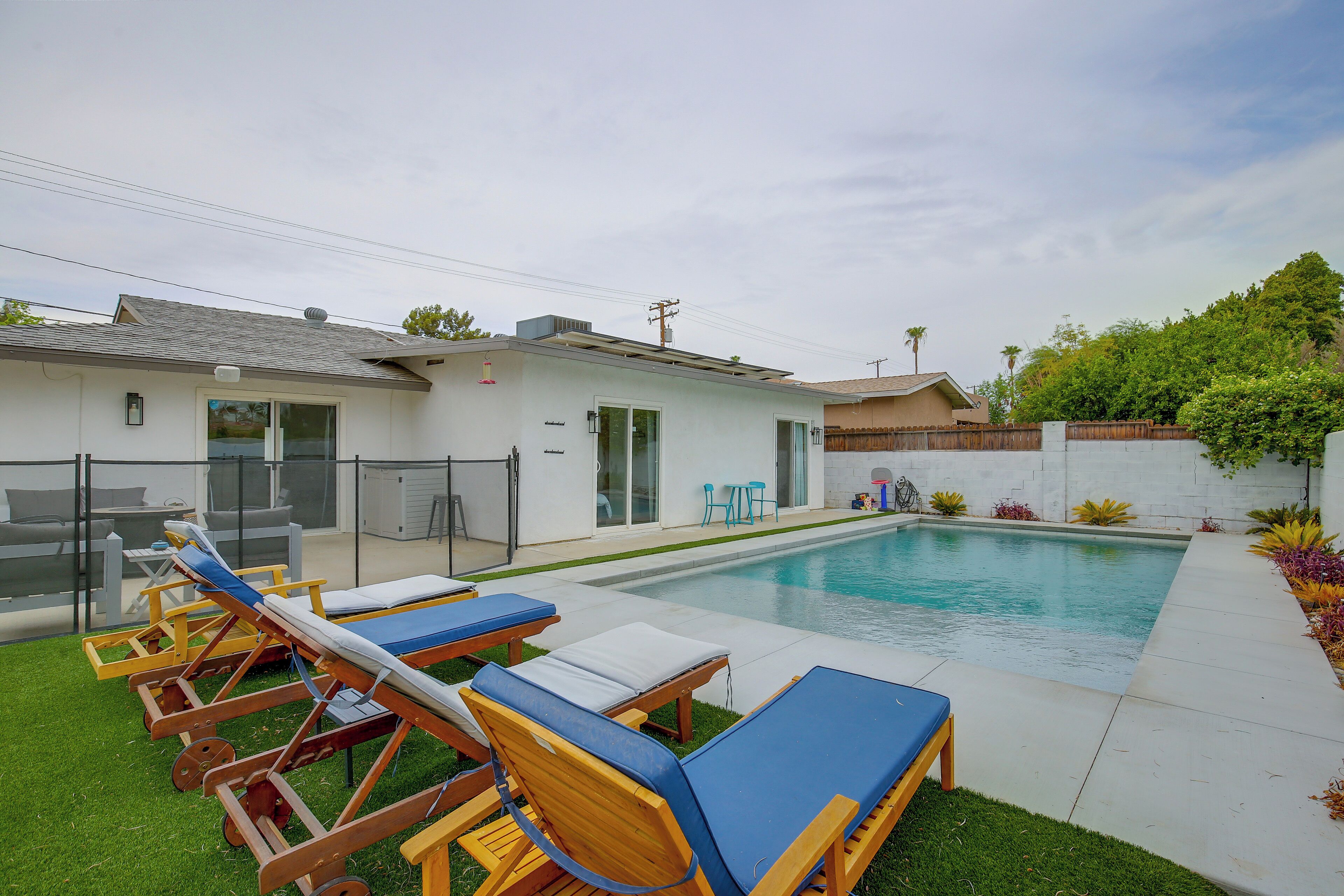 Ein Garten mit Pool, Liegestühlen und einer kleinen Terrasse.