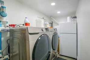 A compact laundry room with a front-loading washing machine, a dryer, and a refrigerator. - Grill & Fire Pit! Palm Desert Extended Escape (Palm Desert)