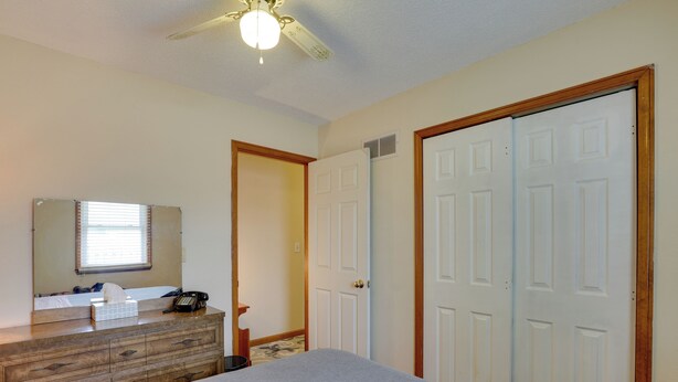 A hotel room with a bed, dresser, mirror, and two white doors.