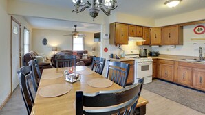 A dining area with a wooden table and chairs, a kitchen with wooden cabinets and appliances, and a ceiling fan.