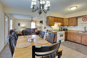 A dining area with a wooden table and chairs, a kitchen with wooden cabinets and appliances, and a ceiling fan.