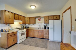 A compact kitchen with wooden cabinets, a stove, a refrigerator, and a coffee maker.