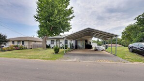 A single-story house with a covered porch, a fenced yard, and a parked car.