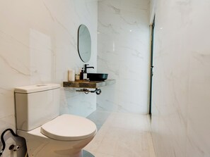 A modern bathroom with a toilet, a sink with a black basin, and a mirror on the wall.