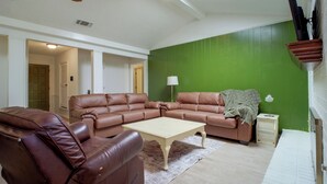 Una sala de estar con un sofá modular, una mesa de centro y una pared de acento verde.
