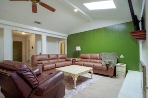 Ein Wohnzimmer mit einer Eckcouch, einem Couchtisch und einer grünen Akzentwand.