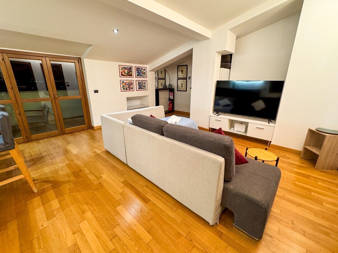 Uma sala de estar moderna com um sofá, uma televisão e piso de madeira.