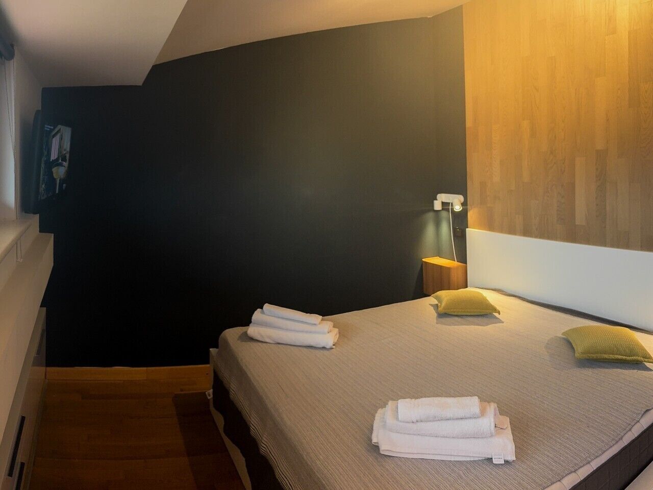 A hotel room with a bed, a nightstand, a lamp, and a wall-mounted picture.