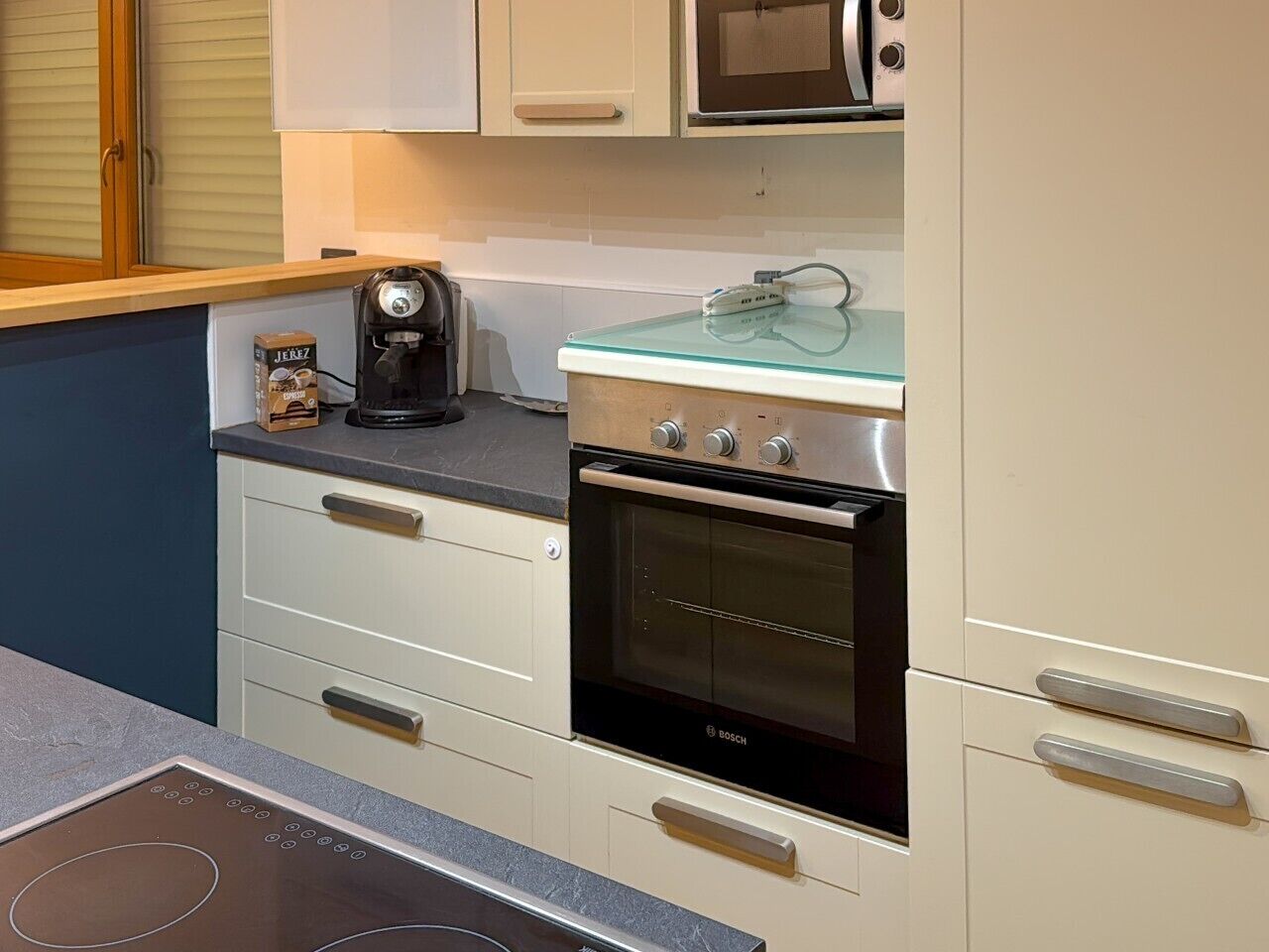 Uma cozinha com forno Bosch, cafeteira e micro-ondas na bancada.