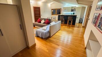Ein modernes Wohnzimmer mit einer Couch, einem kleinen Tisch und einer Küchenzeile im Hintergrund.