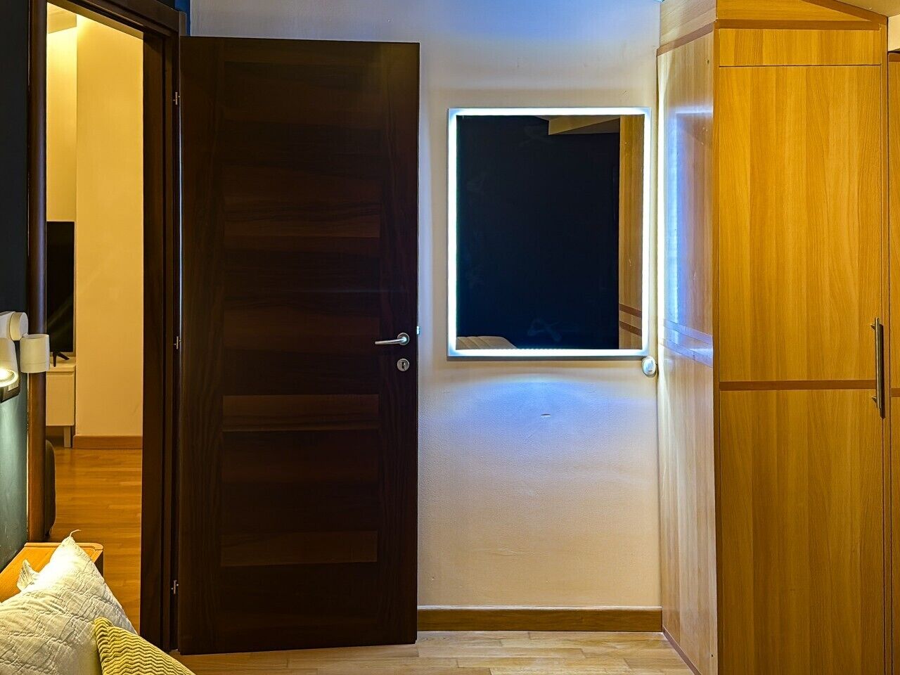 A room with a wooden door, a small window, and a wardrobe.