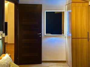 Ein Zimmer mit Holztür, kleinem Fenster und Kleiderschrank.