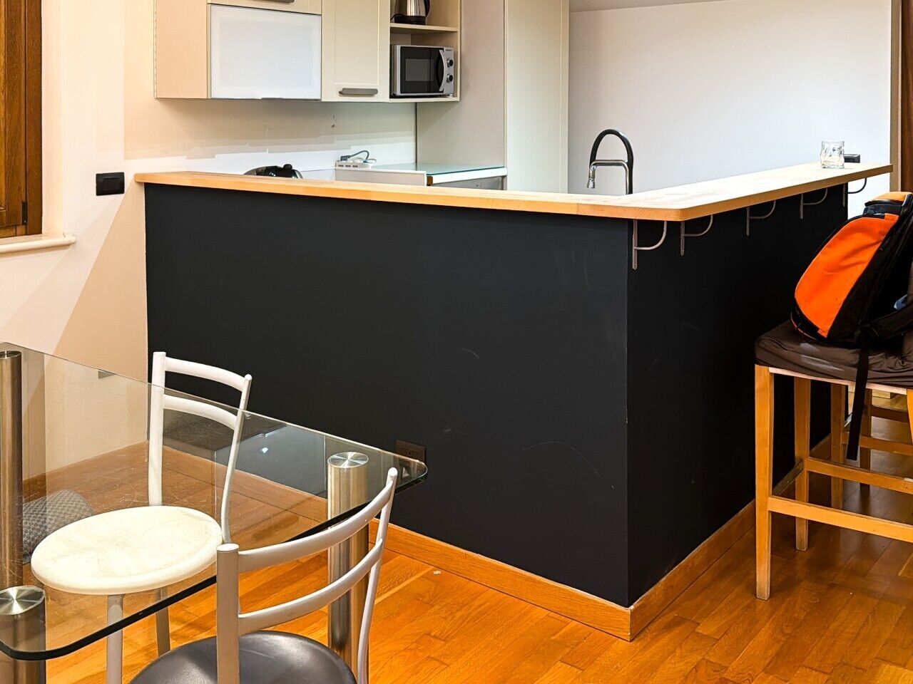 Une cuisine compacte dotée d’un îlot central, d’une table à manger avec des chaises et d’un four à micro-ondes placé au-dessus de l’îlot.
