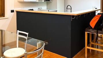 Une cuisine compacte dotée d’un îlot central, d’une table à manger avec des chaises et d’un four à micro-ondes placé au-dessus de l’îlot.