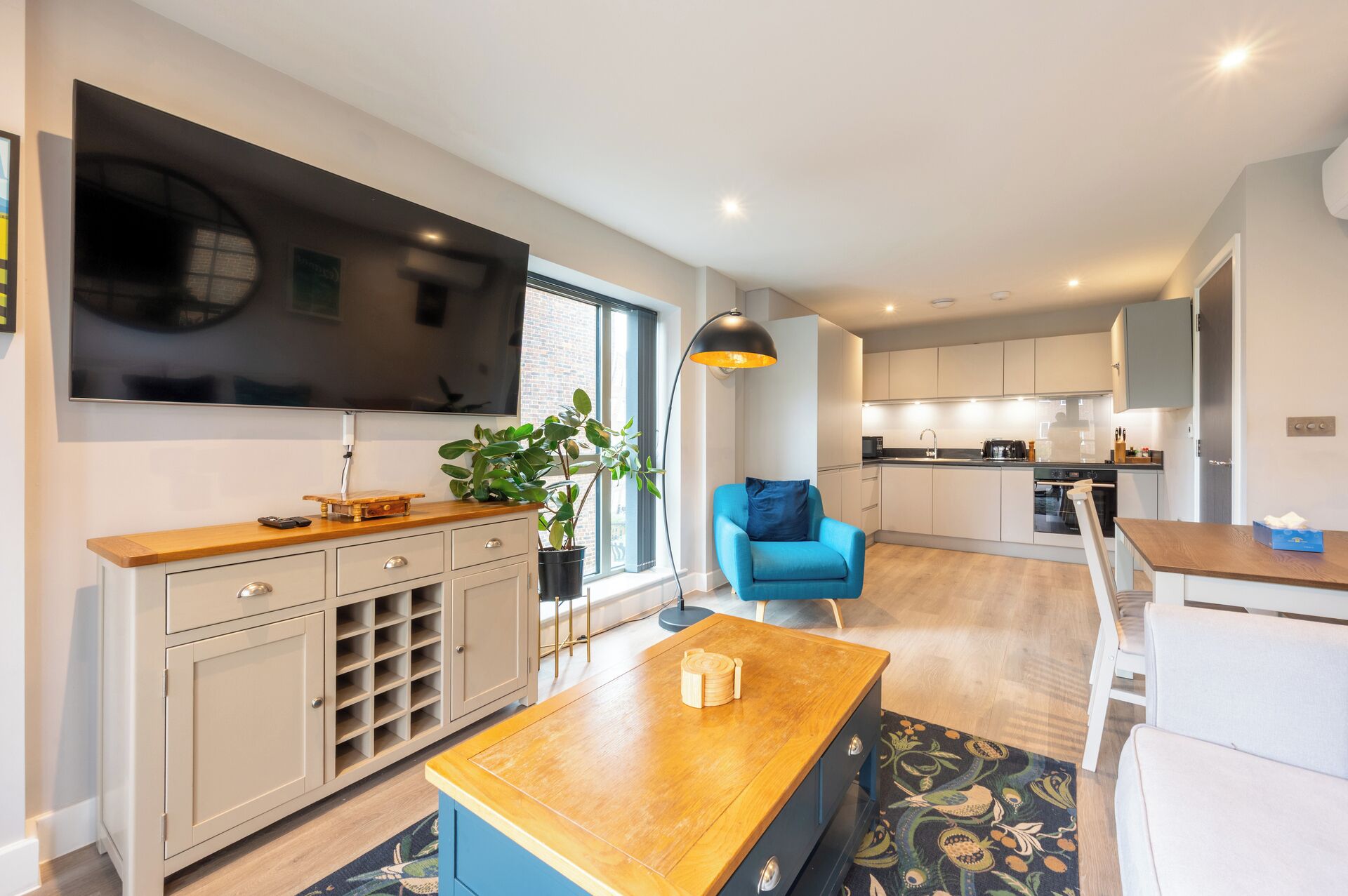 A modern living room with a TV, wooden coffee table, and a blue armchair.