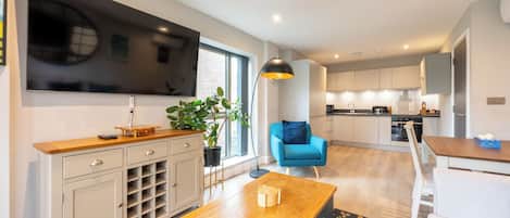 A modern living room with a TV, wooden coffee table, and a blue armchair.