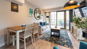 En moderne stue med spiseplads, sofa, sofabord og et stort vindue med byudsigt.