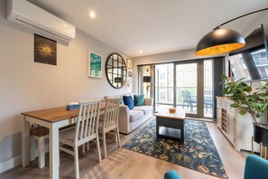 Ein modernes Wohnzimmer mit Essbereich, einer Couch, einem Couchtisch und einem großen Fenster mit Stadtblick.