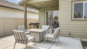 Une terrasse extérieure avec une table et des chaises, un barbecue et un espace abrité avec une fenêtre.