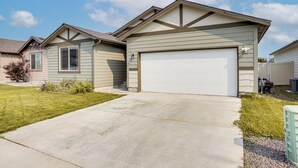 Une maison d’habitation avec un garage, une allée et une pelouse.