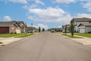 A residential street with houses on both sides, a clear sky, and a few parked cars. - 3 Mi to Spokane River! Furnished Patio & Yard (Post Falls)