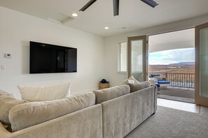 A living room with a sectional sofa, a mounted TV, and a view of a balcony with a railing. - Resort-Style St George Casita w/ Lagoon Access (St. George)