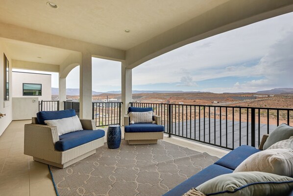 A balcony with wicker furniture, a patterned rug, and a view of a desert landscape.