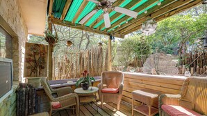 Een terras buiten met rieten meubilair, een plafondventilator en een decoratieve plant.