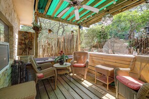 Eine Terrasse im Freien mit Korbmöbeln, einem Deckenventilator und einer Zierpflanze.
