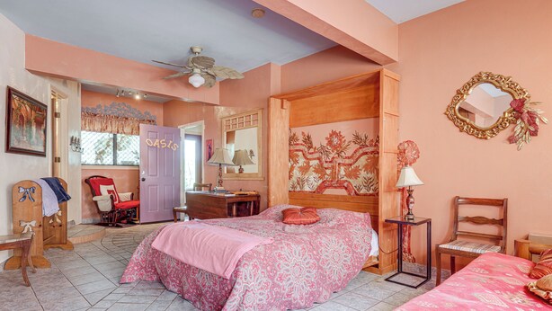 Een slaapkamer met een bed, een stoel, een bureau en een spiegel.