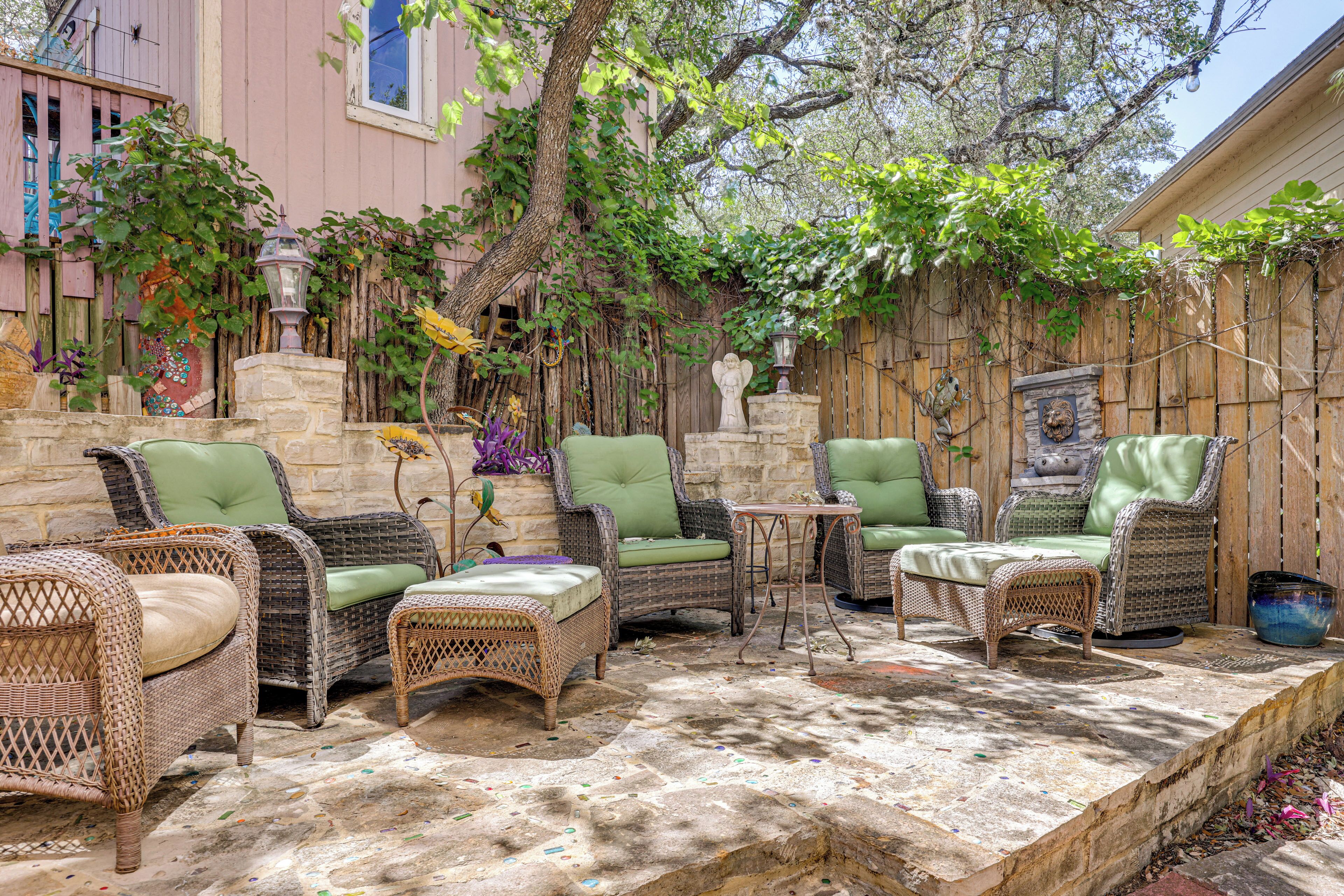 A patio area with wicker furniture and a stone floor.