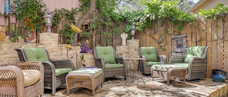 A patio area with wicker furniture and a stone floor.