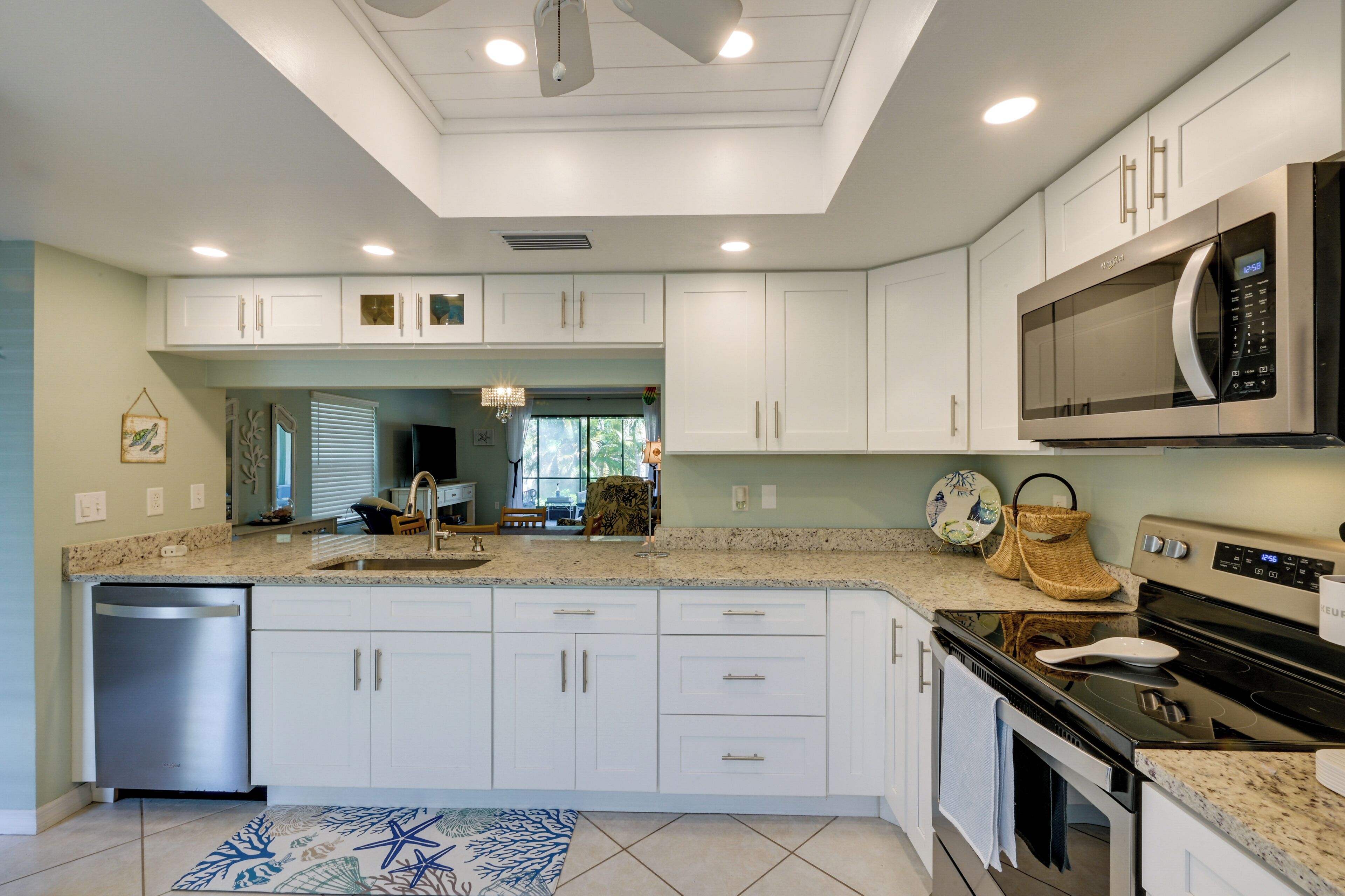 A modern kitchen with white cabinets, a stainless steel microwave, and a granite countertop.