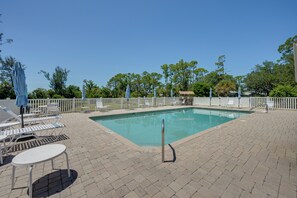 A rectangular pool with a white fence surrounding it, lounge chairs, and umbrellas on a paved patio. - Walk to the Gulf Coast! 55+ Retreat w/ Pool Access (Englewood)