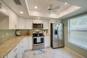 A modern kitchen with white cabinetry, stainless steel appliances, a microwave, oven, and refrigerator. - Walk to the Gulf Coast! 55+ Retreat w/ Pool Access (Englewood)
