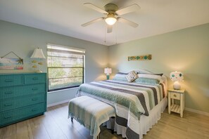 Une chambre à coucher avec un lit, une commode, une fenêtre et un ventilateur de plafond.