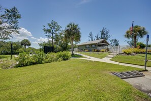 A well-maintained grassy area with a pathway leading to a building with a covered porch. - Walk to the Gulf Coast! 55+ Retreat w/ Pool Access (Englewood)