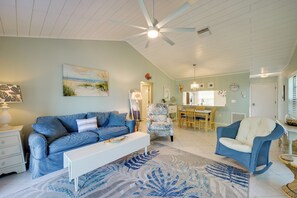 A living room with a blue sofa, a white coffee table, and a patterned rug. - Walk to the Gulf Coast! 55+ Retreat w/ Pool Access (Englewood)