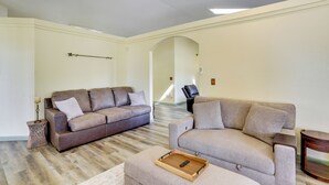Un salón amplio con un sofá de cuero marrón, un sillón beige y una mesita de madera.