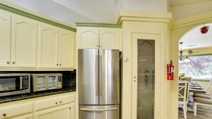 Una cocina con un refrigerador de acero inoxidable, un microondas y un comedor con mesa y sillas.