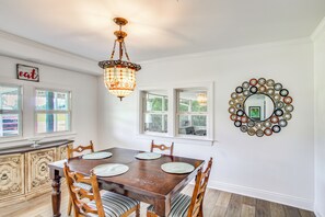 A dining area with a wooden table, chairs, a chandelier, and a decorative mirror on the wall. - Great for Families! Dothan Getaway w/ Large Yard (Dothan)
