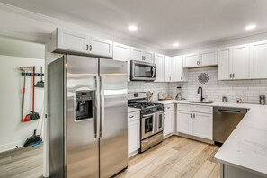 A modern kitchen with stainless steel appliances, white cabinetry, and a wooden floor. - Great for Families! Dothan Getaway w/ Large Yard (Dothan)