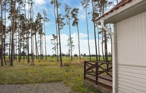 A wooden cabin with a porch, surrounded by a forest of tall trees and a grassy field. - Gorgeous home in Gärds Köpinge with WiFi (Gärds Köpinge)